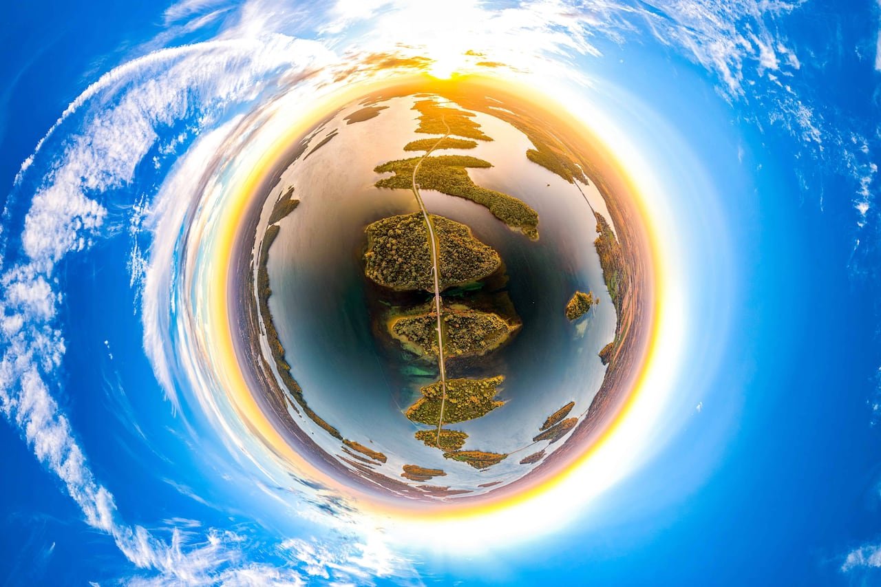 A sphere resembling a planet surrounded by an orange ring with a connecting roadway among several islands.